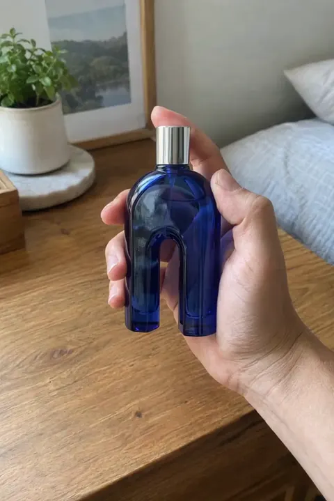 Actual Aisma result: The same hand turning a cobalt-blue arch-shaped bottle.